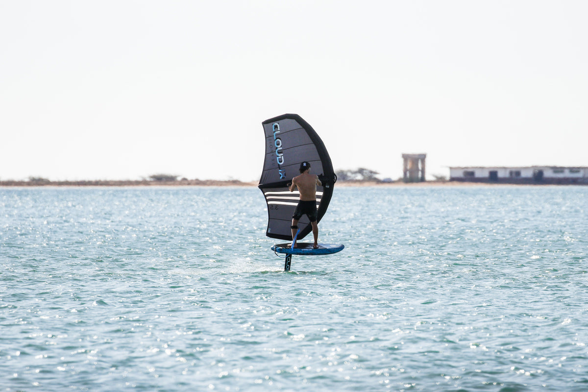 Pratiquant de wingfoil en vol sur le lagon